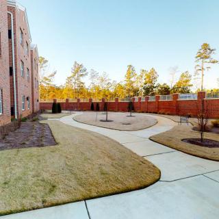 A landscaped courtyard with pathways and surrounding trees beside a building.
