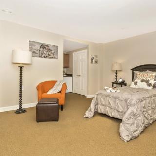 A cozy bedroom featuring a comfortable bed, an orange chair with a footrest, and elegant decor.