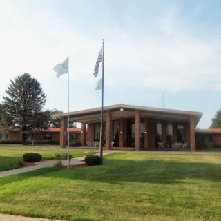 A modern architectural building with flags in front, set in a landscaped area.