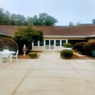 A suburban house with a courtyard featuring outdoor seating and landscaped bushes.