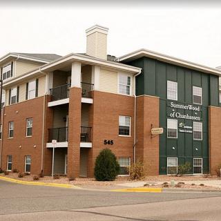 A three-story residential building with brick and green siding in an urban area.