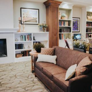 A cozy living room with a sofa, bookshelves, and a fireplace.