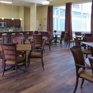 A spacious dining area with wooden floors and a connected kitchen.