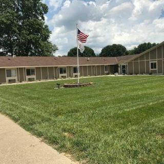 A large building with a well-maintained lawn and an American flag flying in the yard.