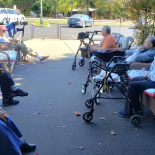 Elderly residents enjoy a sunny day outside a care facility.