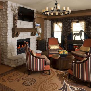 A cozy living room with a fireplace, seating area, and decorative chandelier.