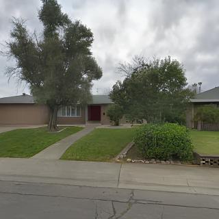 A suburban residential house with a lawn and trees.