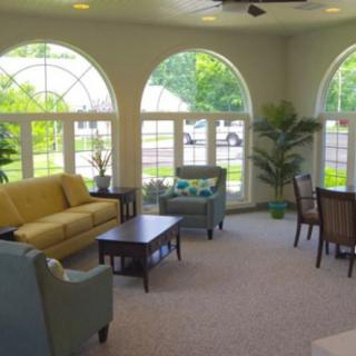 A cozy living room with large arched windows, comfortable seating, and abundant natural light.