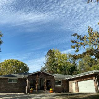 A suburban house with a clear blue sky and surrounding trees.