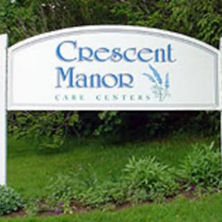 A sign for Crescent Manor Care Center surrounded by greenery.