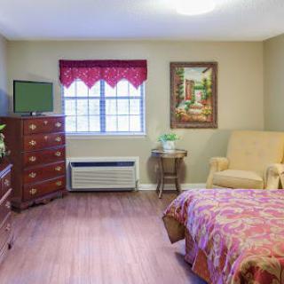 A cozy bedroom with a comfortable armchair, dresser, and decorative elements.