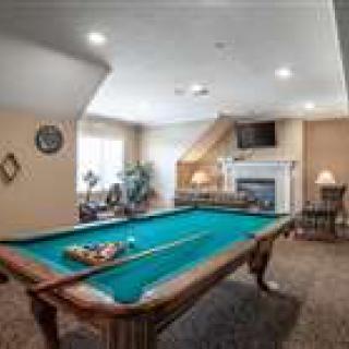 A cozy game room featuring a pool table, fireplace, and television.
