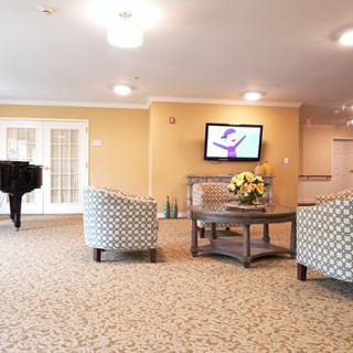 A cozy lounge area featuring comfortable seating, a television, and a grand piano.