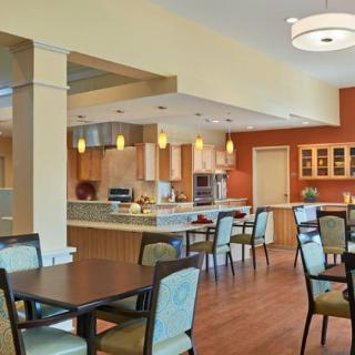 A modern dining area with tables and chairs, adjacent to a kitchen space.
