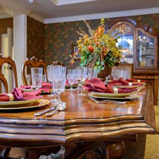 A beautifully set dining table with elegant tableware and a vibrant floral centerpiece.