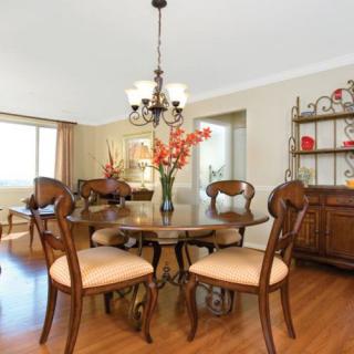 A classic dining room with a wooden table, upholstered chairs, and a chandelier above.