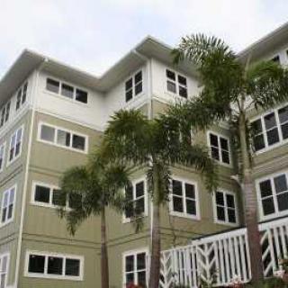 A multi-story residential building with palm trees in front.