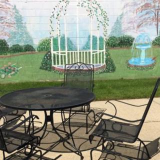A patio set in front of a garden mural, depicting a gazebo and fountain.