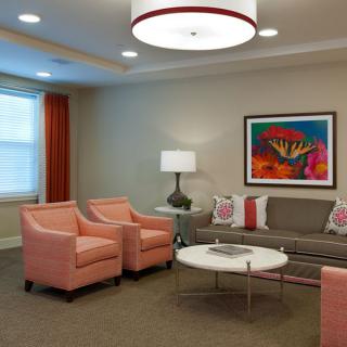 A stylish living room with coral armchairs, a gray sofa, and vibrant artwork on the wall.