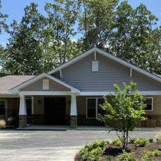 A charming residential house with a gabled roof, surrounded by trees and a well-maintained front yard.