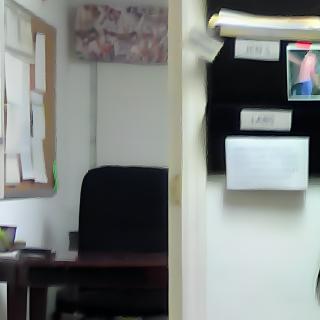 An empty office space with a desk, chair, and bulletin board filled with documents.