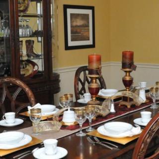 A formal dining room with an elegantly set table, complete with plates, cups, and decorative candles.