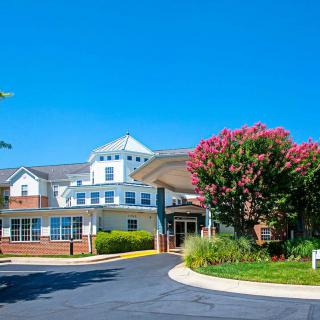 A sunny day view of a building surrounded by trees and flowers.
