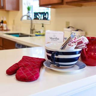A cozy kitchen setup featuring a striped mug with utensils and a red oven mitt on the countertop.