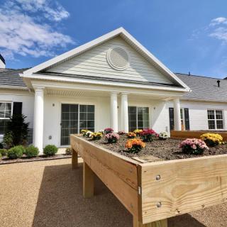 A beautiful residential house with a raised garden bed filled with colorful flowers on a sunny day.