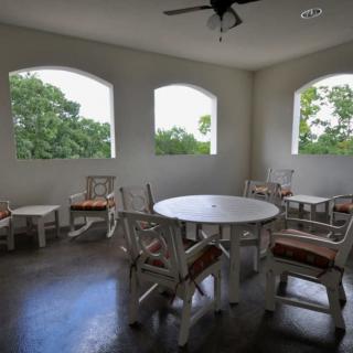 A cozy indoor dining area with a round table and chairs, illuminated by natural light through large windows.