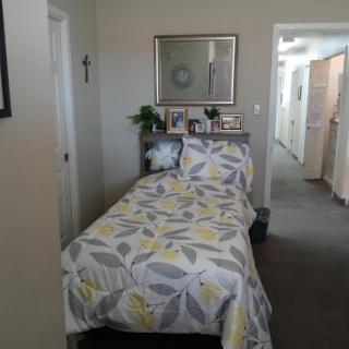 A cozy bedroom featuring a single bed with floral bedding and personal touches.