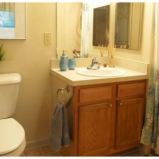 A cozy bathroom with a wooden vanity, sink, and mirror.