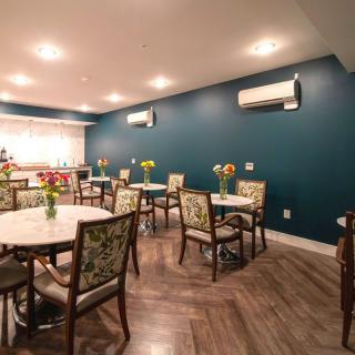 A cozy dining area with elegant decor, featuring tables adorned with floral arrangements and a modern design aesthetic.