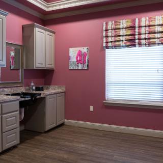 A cozy kitchen space featuring pink walls and modern cabinetry, illuminated by natural light from a window.