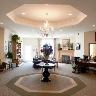 An elegant lobby featuring a chandelier, central table with floral arrangement, and cozy seating area.