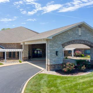 A modern building with a paved entrance and landscaped surroundings under a clear blue sky.