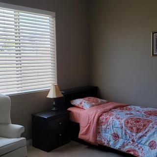 A small, cozy bedroom with a single bed and natural light streaming through the window.