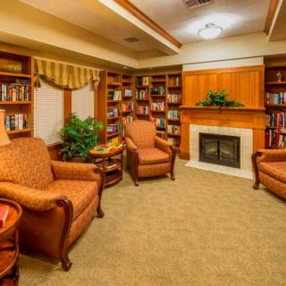 A cozy reading room with comfortable armchairs, a fireplace, and well-stocked bookshelves.