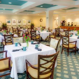 An elegant restaurant interior featuring neatly arranged tables with white tablecloths and comfortable chairs.