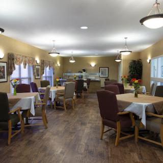 A cozy dining area with tables set for meals, featuring warm lighting and comfortable seating.
