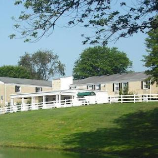 A charming residential house with a well-manicured lawn and surrounding trees.