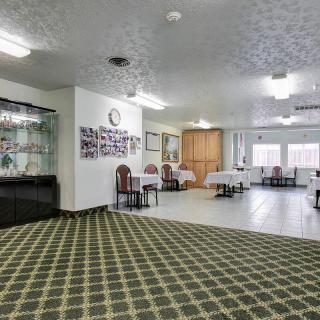A spacious hotel lobby with carpet flooring and tables set with white tablecloths.