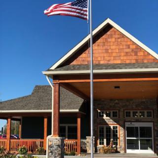 A building with an American flag flying in front, showcasing its architecture under a clear blue sky.
