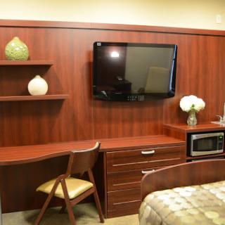 A cozy interior featuring a wooden desk, a wall-mounted television, and a microwave in a neatly arranged living space.