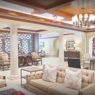 A luxurious and elegantly designed living room with plush sofas, a chandelier, and decorative pillars.