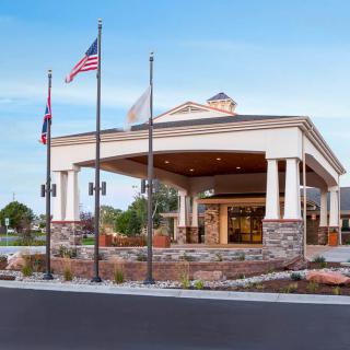 A modern hotel entrance with flags and landscaped surroundings.