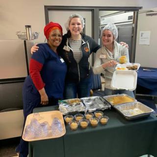 A joyful gathering featuring three women celebrating with delicious food.