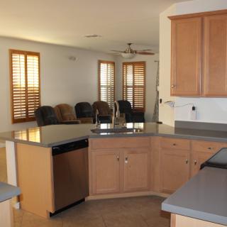 An open kitchen with wooden cabinets and a view into a living area.