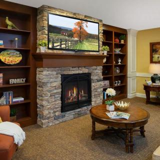 A cozy living room with a stone fireplace, built-in bookshelves, and a television mounted above the mantel.