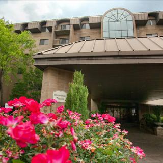 A picturesque view of a hotel entrance surrounded by vibrant flowers.